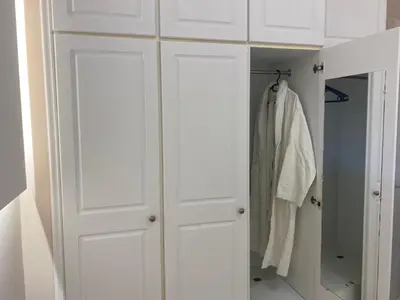 a white closet with white cabinets and a robe at Comfortable Apartment Near to Metro in Athens