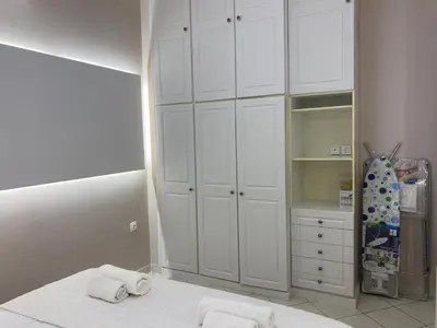 a bedroom with white cabinets and towels on a bed at Comfortable Apartment Near to Metro in Athens