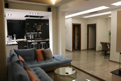 a living room with a blue couch and a kitchen at Exzellent ApartAthens 120qm, near Metro M2 in Athens