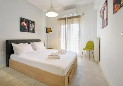 a bedroom with a bed and a green chair at Cosy 2BR flat near Ampelokipoi station & hospitals in Athens
