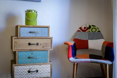 a room with a chair and a table with drawers at Cosy 2BR flat near Ampelokipoi station & hospitals in Athens