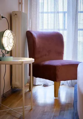 a brown chair sitting next to a table with a lamp at Cosy 2BR flat near Ampelokipoi station & hospitals in Athens