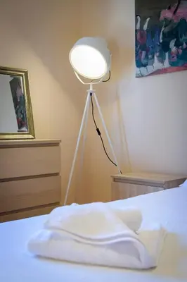 a lamp sitting next to a bed with a white sheet at Cosy 2BR flat near Ampelokipoi station & hospitals in Athens