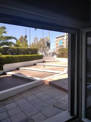an open glass door of a building with a courtyard at Glyfada First Center in Athens