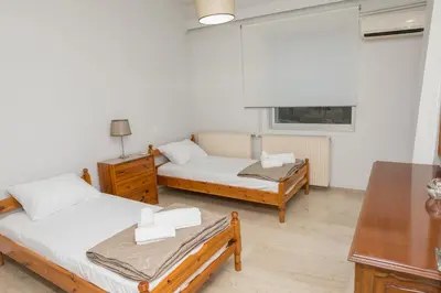 a bedroom with two beds and a table and a window at Saronicos Gulf View in Anavissos in Anavissos