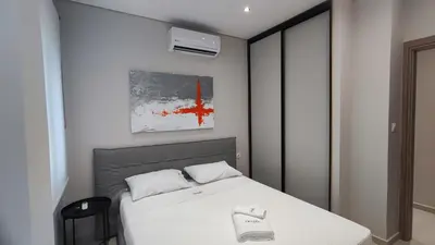 a small bedroom with a white bed and a black stool at Luxury Apartment Stella in Piraeus