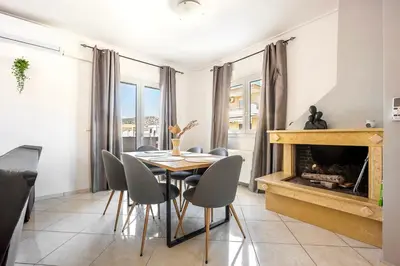a dining room with a fireplace and a table and chairs at Mountain-to-Sea Oasis in Kalívia Thorikoú