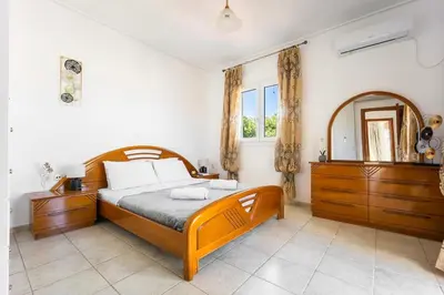 a bedroom with a wooden bed and a mirror at Mountain-to-Sea Oasis in Kalívia Thorikoú