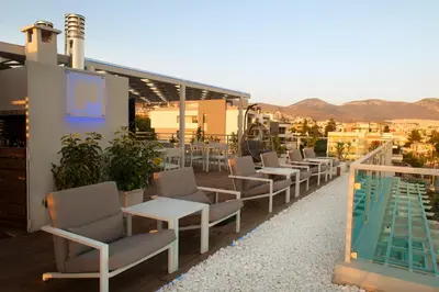 a row of chairs and tables next to a swimming pool at Scale Suites in Athens