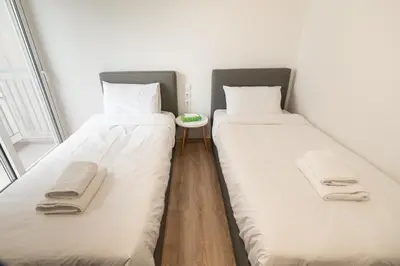 two beds in a small room with a table at LIV - Luminous & Spacious in Pagrati in Athens
