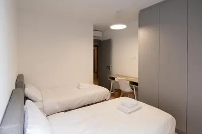 two beds in a room with a desk and a table at LIV - Luminous & Spacious in Pagrati in Athens