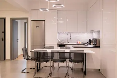 a kitchen with white cabinets and a table with black chairs at LIV - Luminous & Spacious in Pagrati in Athens
