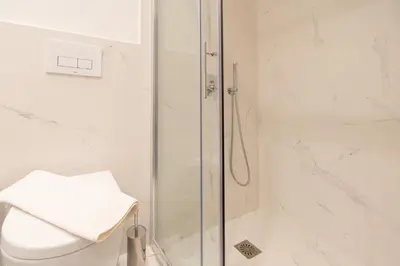 a white bathroom with a shower and a toilet at LIV - Luminous & Spacious in Pagrati in Athens