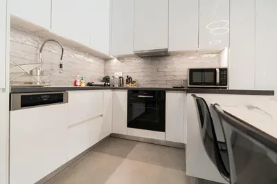 a white kitchen with white cabinets and a microwave at LIV - Luminous & Spacious in Pagrati in Athens