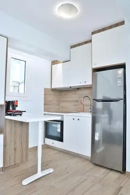 a white kitchen with a refrigerator and a table at LIV - View and the City Studio in Athens in Athens