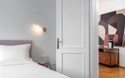 a bedroom with a white bed and a door at The Aeolian in Athens