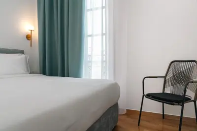 a bedroom with a bed and a chair next to a window at The Aeolian in Athens