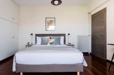 a bedroom with a large bed with white walls at Radiant 2BR Apartment in Neo Psichiko by UPSTREET in Athens