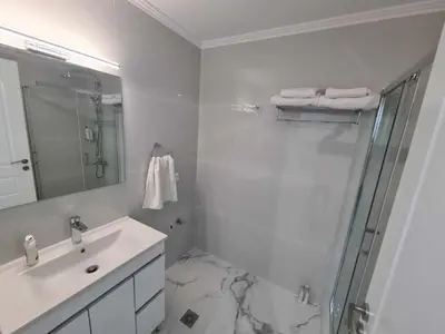 a white bathroom with a shower and a sink at NN Rooms and Suites near Athens Airport in Spáta