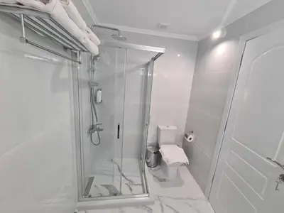 a white bathroom with a shower and a toilet at NN Rooms and Suites near Athens Airport in Spáta