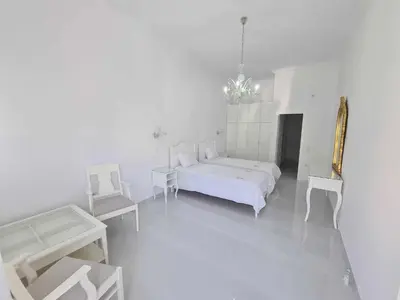 a white bedroom with a white bed and two chairs at NN Rooms and Suites near Athens Airport in Spáta