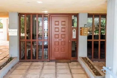 a wooden door on a building with glass windows at V.L.A Apartments by the sea in Vari