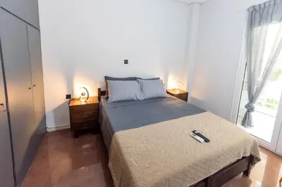 a bedroom with a bed and a large window at V.L.A Apartments by the sea in Vari