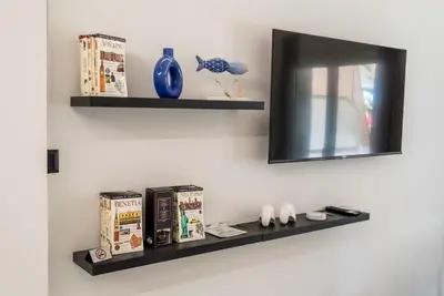 a shelf on a wall with books and a mirror at V.L.A Apartments by the sea in Vari