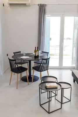 a dining room with a table and chairs with wine bottles on it at V.L.A Apartments by the sea in Vari