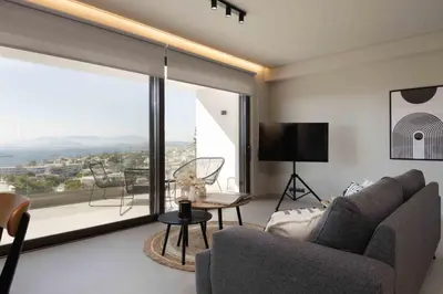 a living room with a couch and a large window at Sunshine Suite by Athens Riviera Suites in Saronida