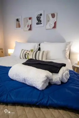 a bed with a blue blanket and pillows on it at Sophia's - Central Apartment Near Egaleo Metro-Athens in Athens