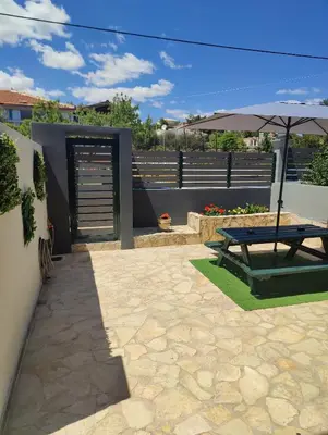 a patio with a picnic table and an umbrella at John's modern apartments artemida in Artemida