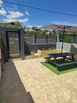 a picnic table with an umbrella on a patio at John's modern apartments artemida in Artemida