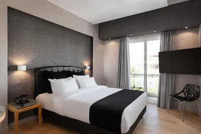 a bedroom with a large bed and a window at Kreoli Suites Glyfada in Athens