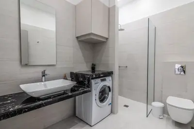 a bathroom with a sink and a washing machine at De lenco Residence 2 in Athens