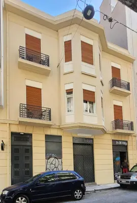 a black car parked in front of a yellow building at De lenco Residence 2 in Athens