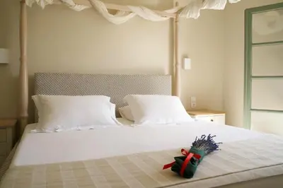 a bed with two pillows and a red ribbon on it at Kores Aegina in Agia Marina Aegina