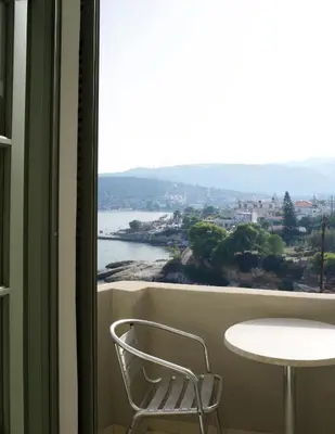 a chair sitting in front of a window with a table at Kores Aegina in Agia Marina Aegina