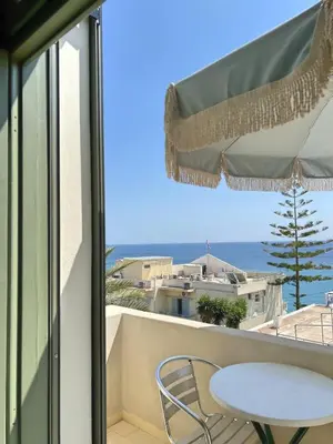 a table and chair on a balcony with a view of the ocean at Kores Aegina in Agia Marina Aegina