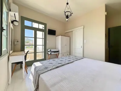 a bedroom with a bed and a desk and a window at Kores Aegina in Agia Marina Aegina