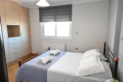 a bedroom with a bed with white sheets and a window at Vasiliki’s Guesthouse in Athens