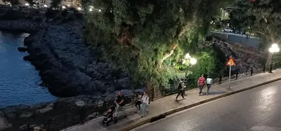 a group of people walking down a sidewalk next to a river at Sea Luxury Apartments in Piraeus