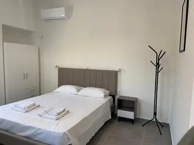 a bedroom with a large white bed and a tv at Leo's Apartments in Koropíon