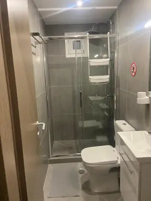 a bathroom with a shower and a toilet and a sink at Leo's Apartments in Koropíon