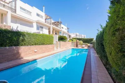 a large blue swimming pool next to a building at Sunset Sea View Maisonette Anavissos in Anavissos