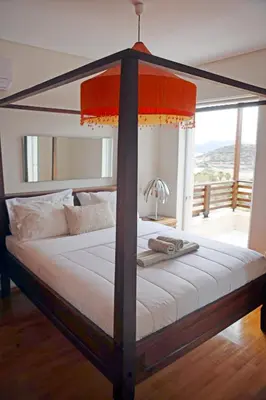 a canopy bed with a white mattress and a window at Sunset Sea View Maisonette Anavissos in Anavissos