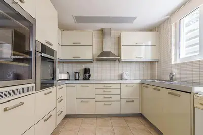 a large kitchen with white cabinets and a window at Sunset Sea View Maisonette Anavissos in Anavissos