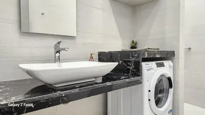 a bathroom with a sink and a washing machine at De lenco Residence 4 in Athens