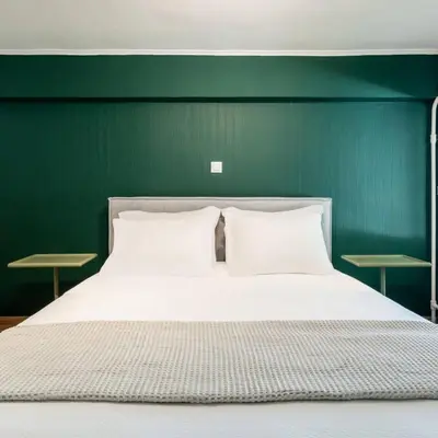 a bed with two pillows and a green wall at 4BD Apartment with Outdoor Jacuzzi Garden in Athens