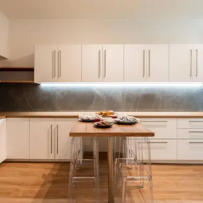 a kitchen with a wooden table and white cabinets at 4BD Apartment with Outdoor Jacuzzi Garden in Athens